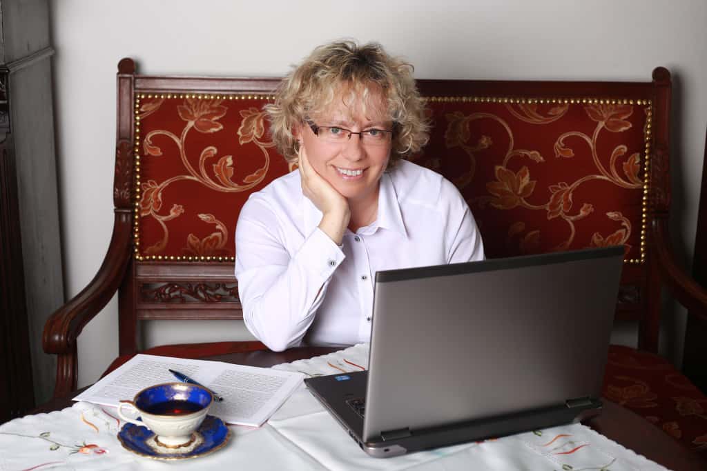 Radna Katarzyna Maciejewska siedzi przy stole przed monitorem komputera