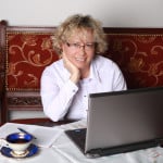 Radna Katarzyna Maciejewska siedzi przy stole przed monitorem komputera
